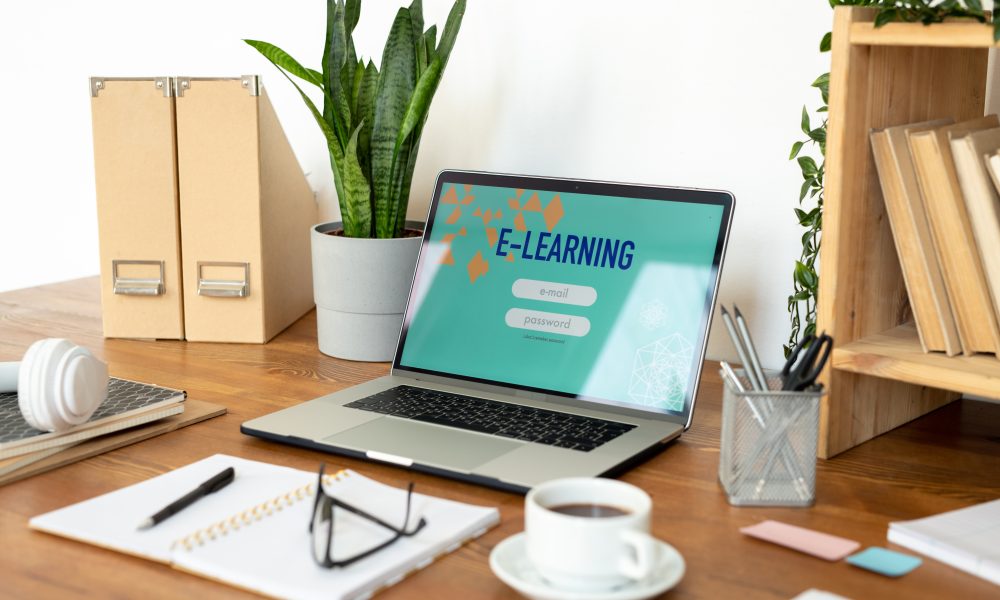 Laptop with website homepage on display surrounded by other office supplies and objects on the desk